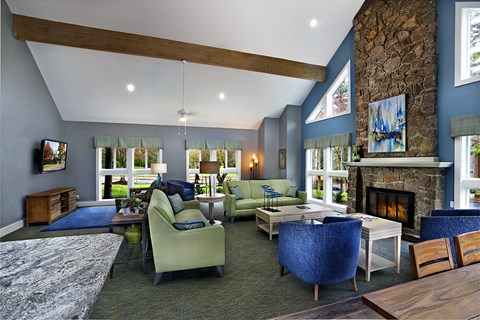 A living room with a stone fireplace and a large window.