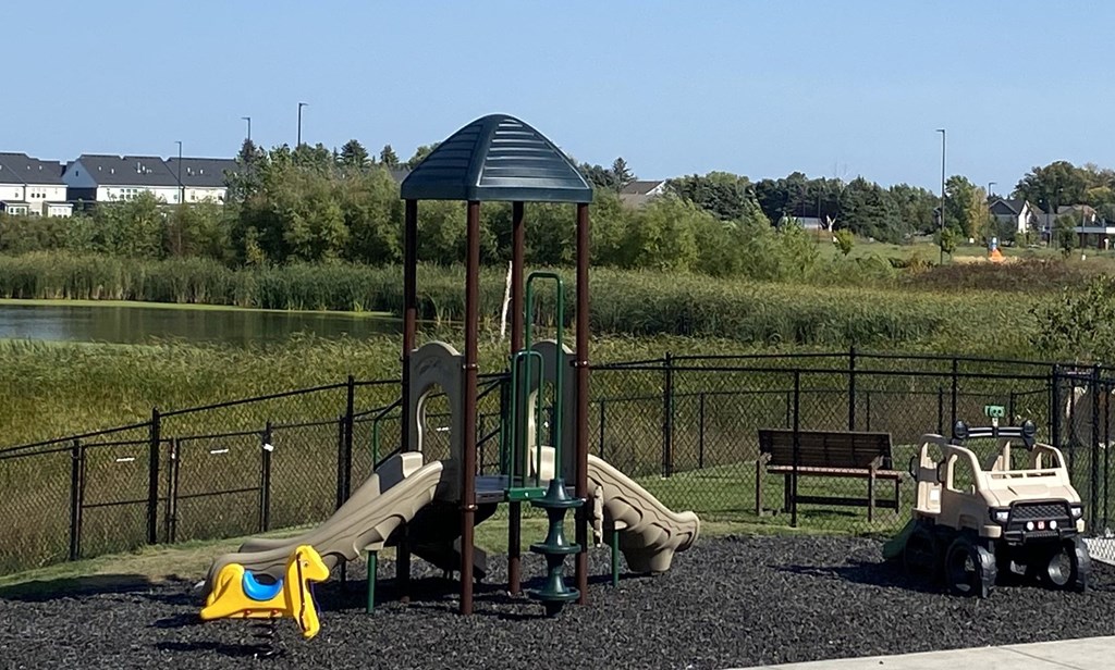 a playground in a park with a pond in the background