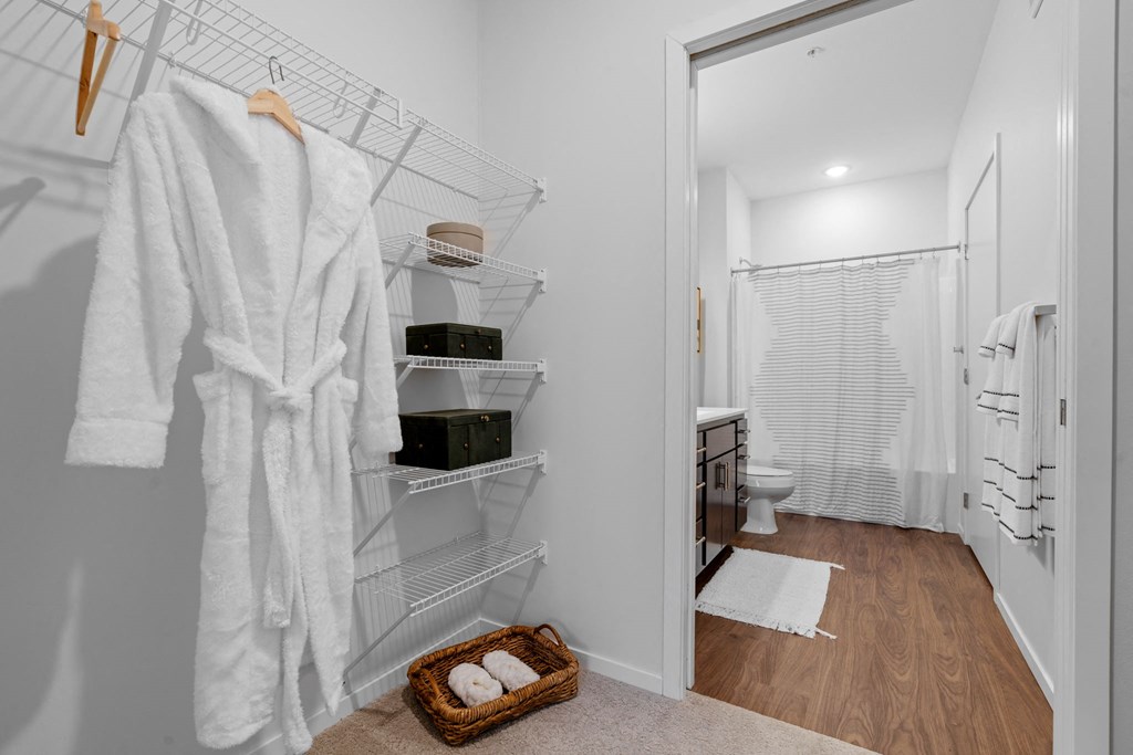 A white bathroom with a white robe hanging on the wall.