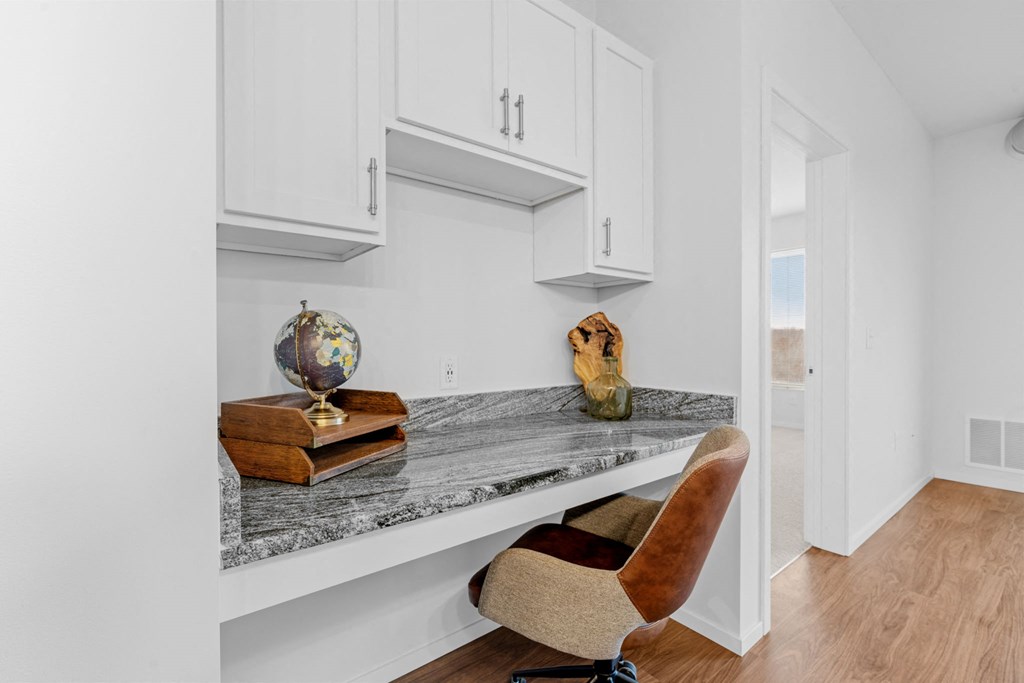 A chair is placed in front of a marble table with a globe and a sculpture on it.