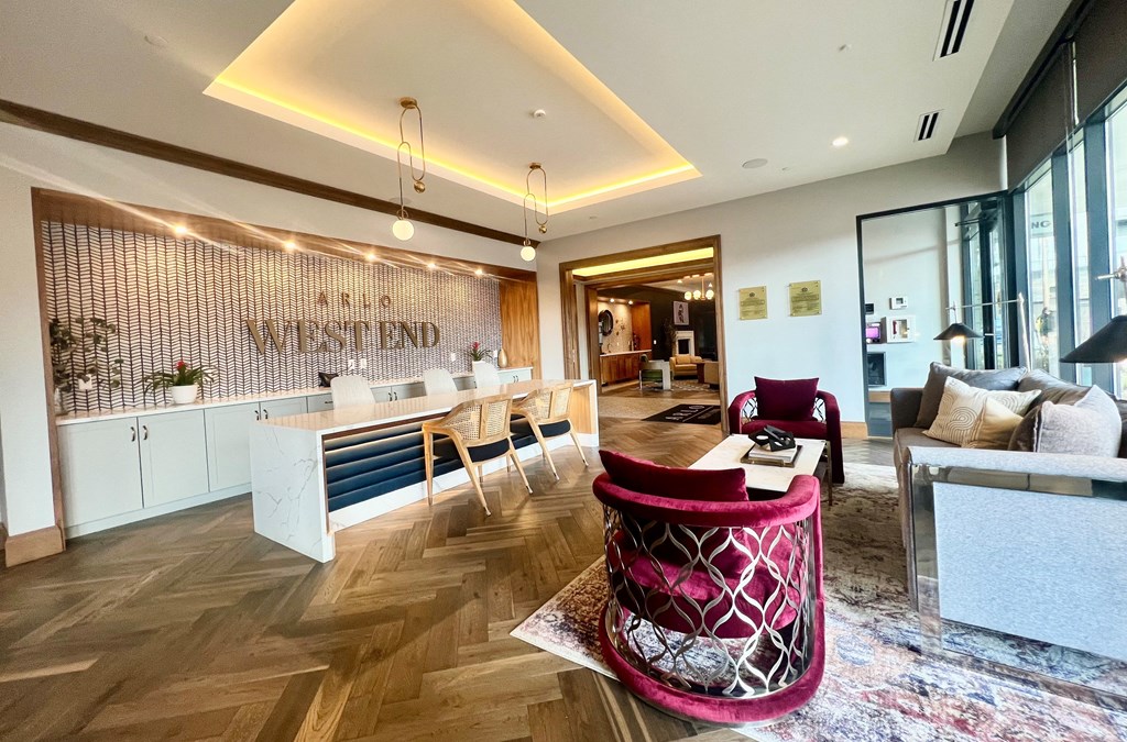 a living room and kitchen in a hotel with a pink chair