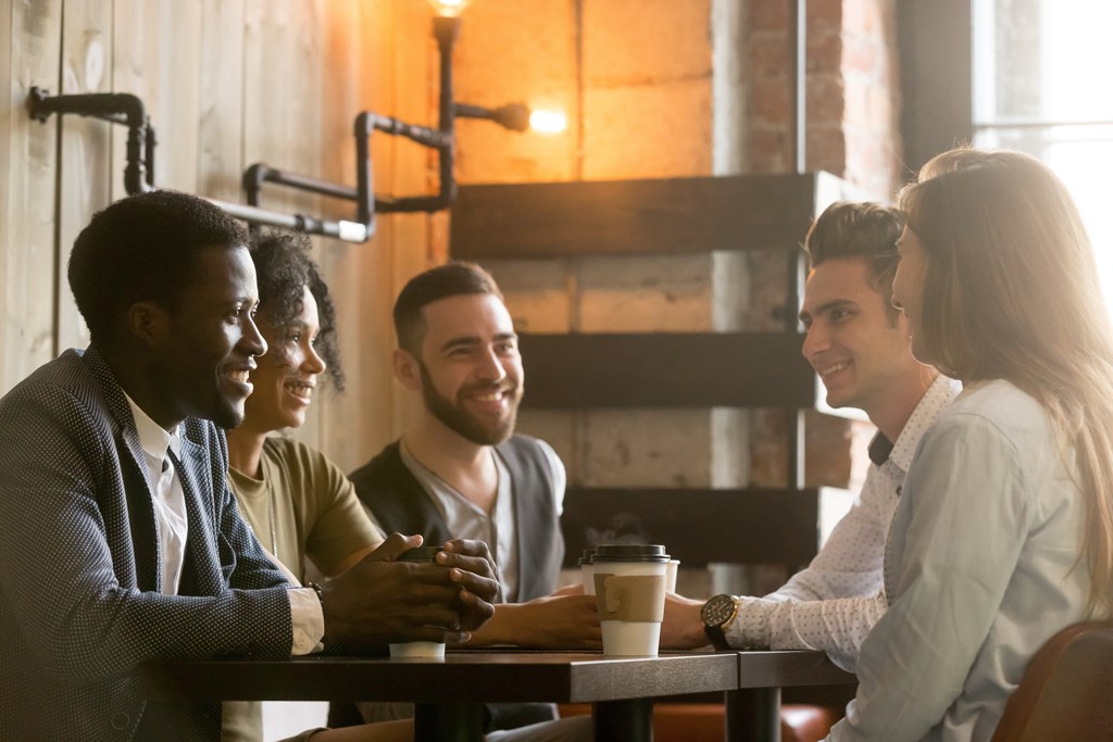 Four people sitting at a table in a cafe.