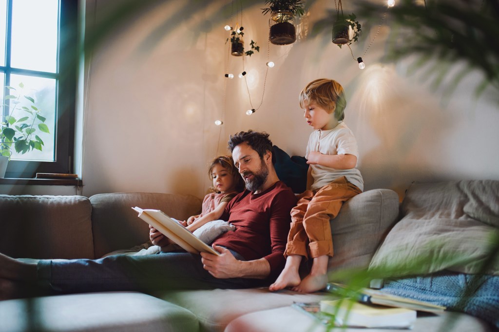 A family of three is sitting on a couch together.