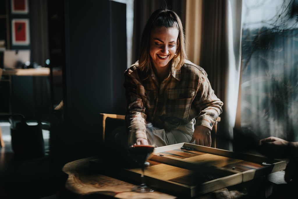 A woman is cutting a vegetable on a wooden cutting board.