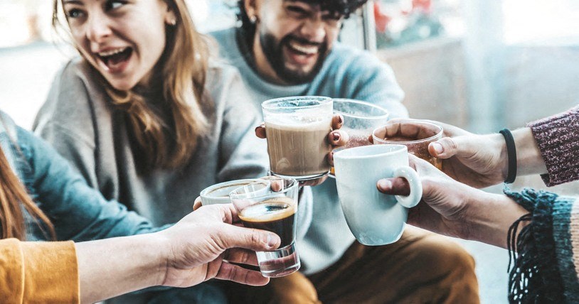 a group of people holding up cups of coffee