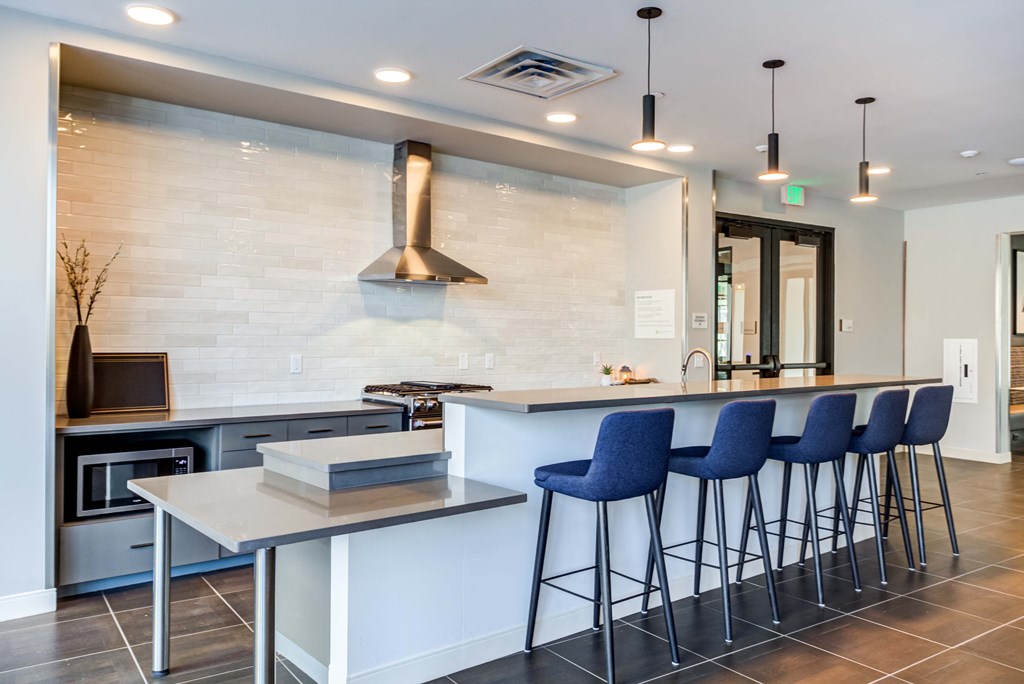 a kitchen with a long counter and blue chairs