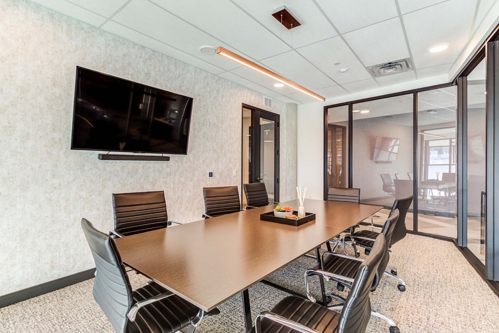 a conference room with a table and chairs and a tv on the wall