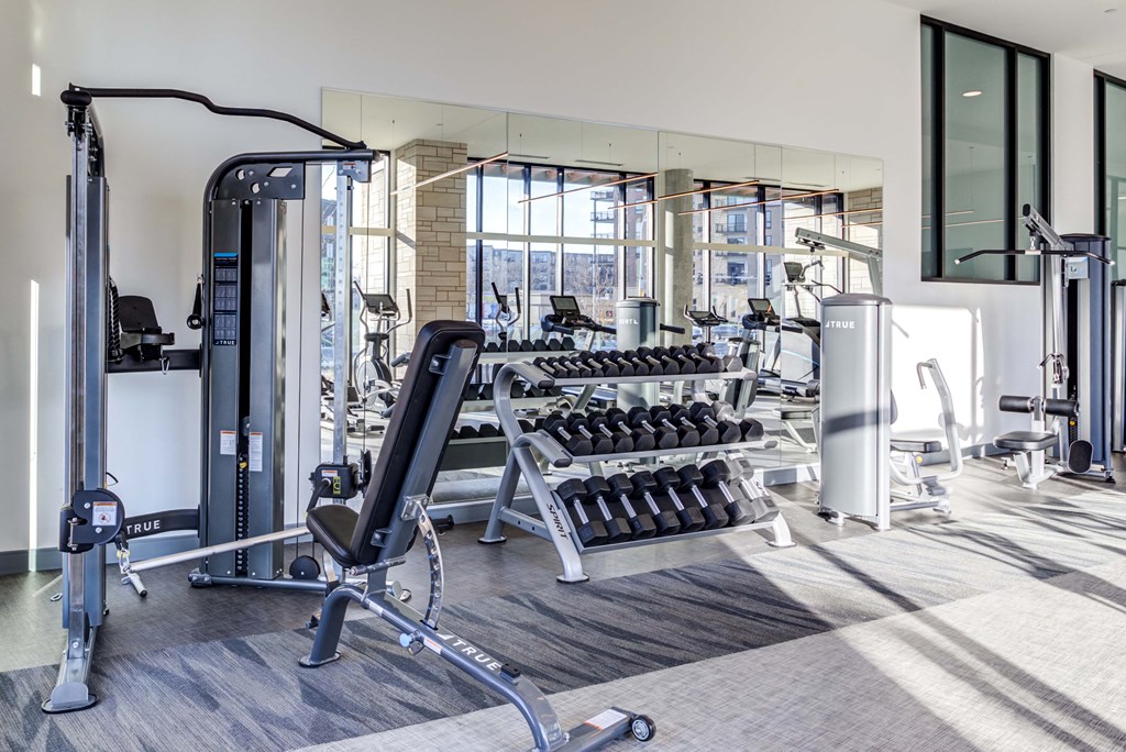 a large fitness room with cardio equipment and a large window