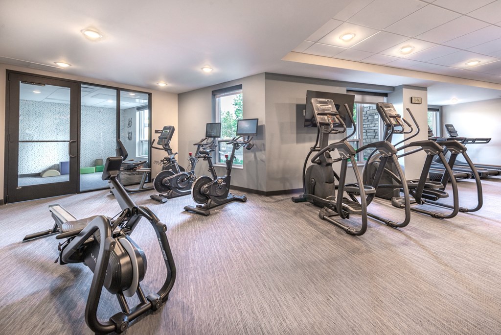 a gym with exercise equipment on the floor and glass doors