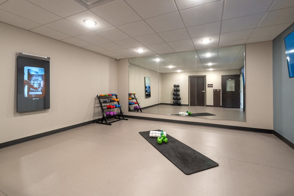 a yoga room with a black mat on the floor and a screen on the wall