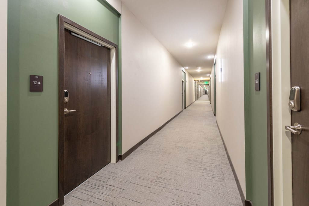 a long hallway with wooden doors and green walls and a tile floor
