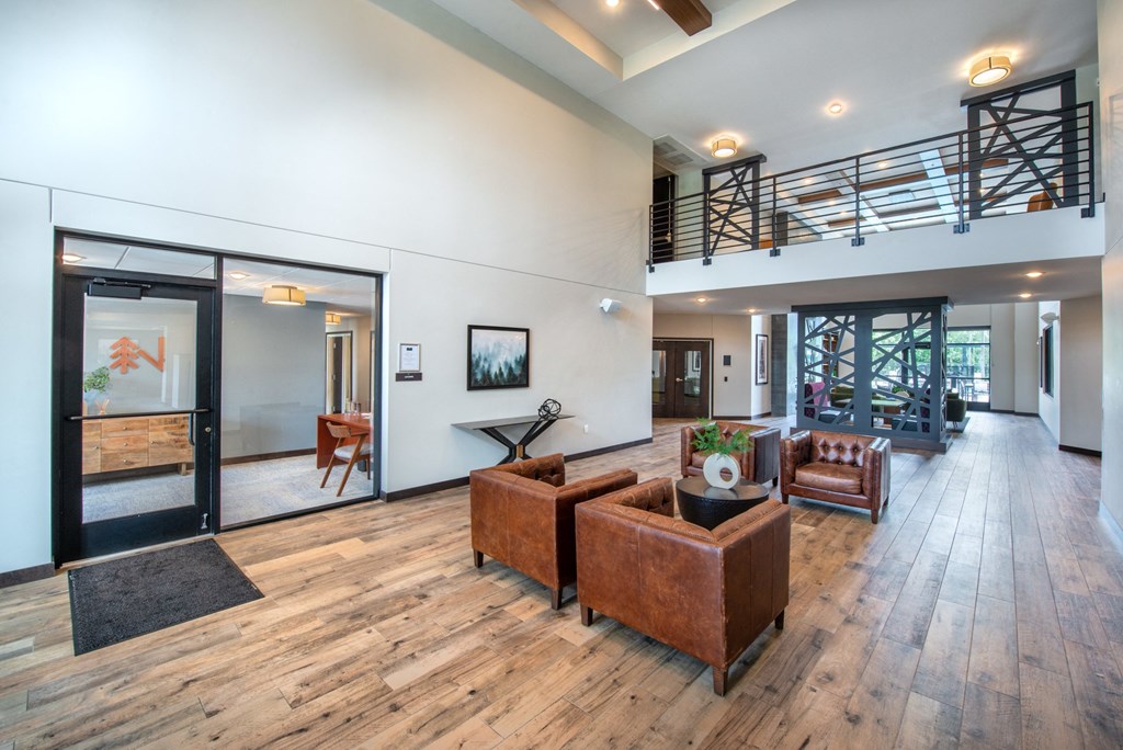 a living room with couches and chairs and a staircase in the distance