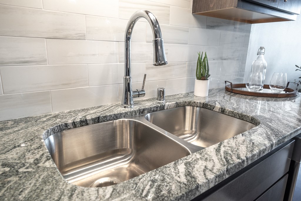 a stainless steel sink in a granite counter top in a kitchen