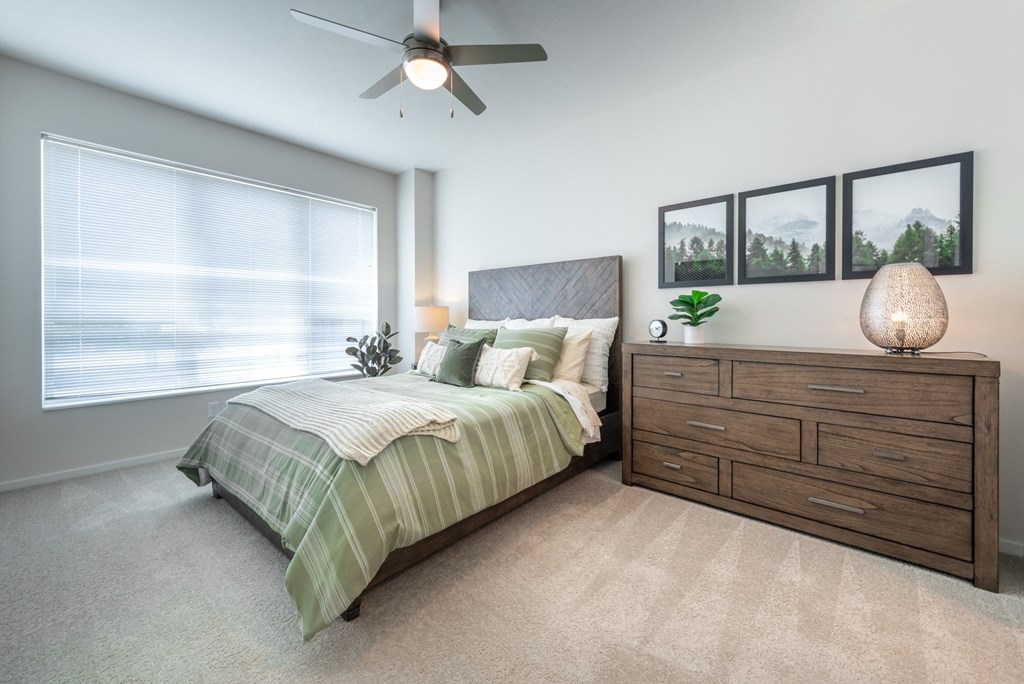 a bedroom with a large window and a ceiling fan