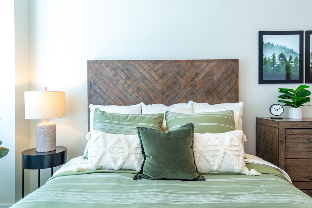 a bedroom with a bed with green pillows and a wooden headboard