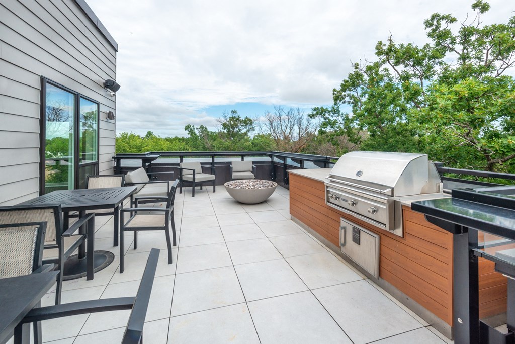 a patio with a grill and tables and chairs