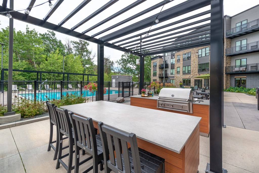 the outdoor kitchen has a large table with chairs and a grill