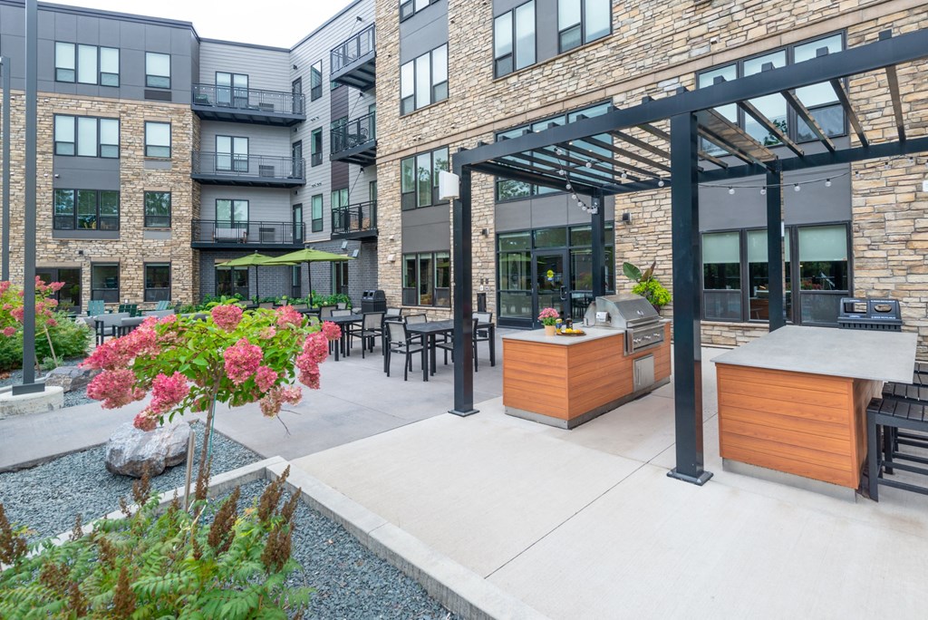 an outdoor patio with a grill and a bar with tables and chairs