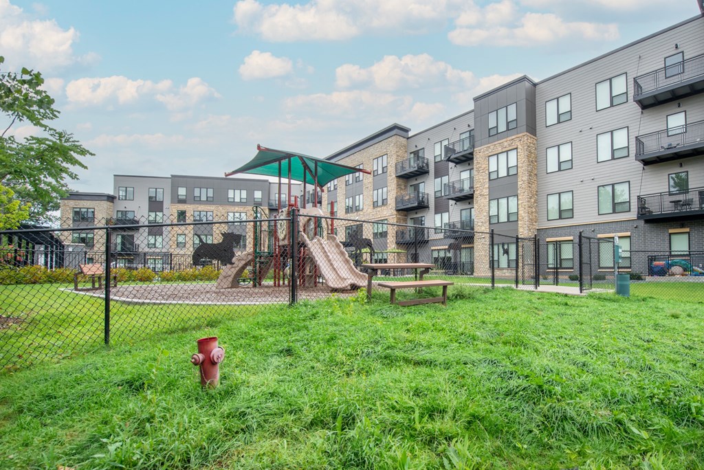 a playground with a swing set in front of an apartment building