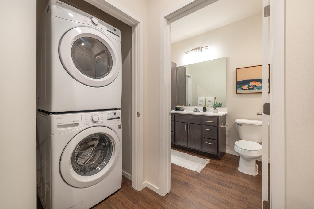 a white washer and dryer in a bathroom with a toilet and a sink