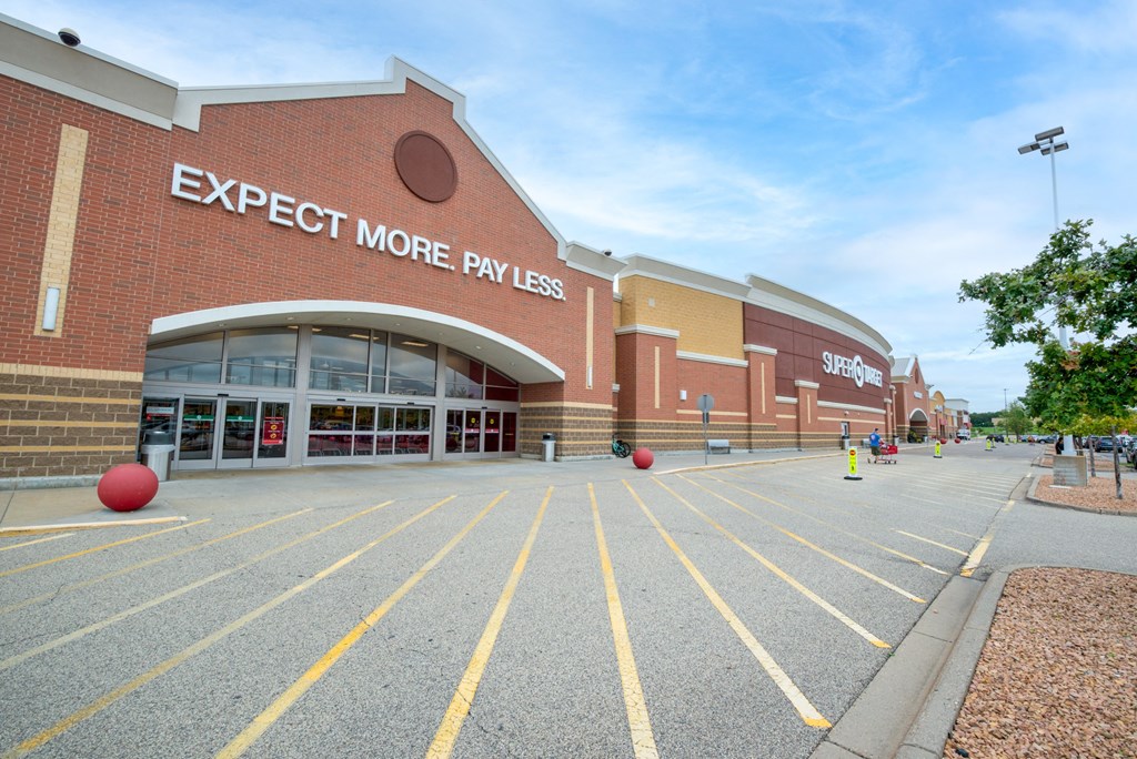 a brick building with a parking lot and a sign that says expect more pay less