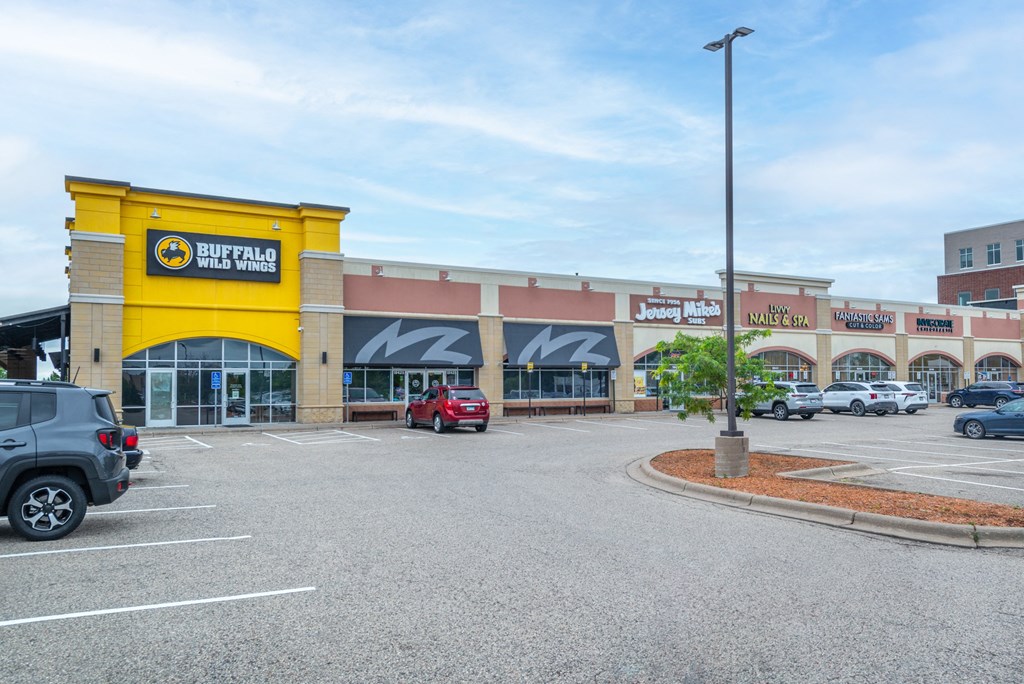 the exterior of a shopping center with cars parked in a parking lot