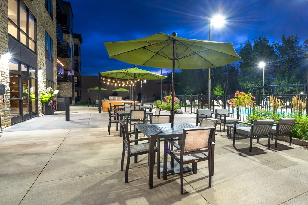 an outdoor patio with tables and umbrellas at night