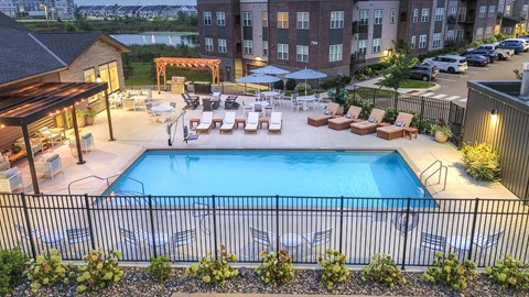 an aerial view of a swimming pool with lounge chairs at night