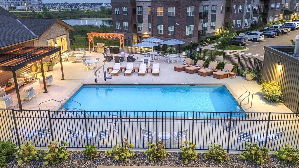 an aerial view of a swimming pool with lounge chairs at night