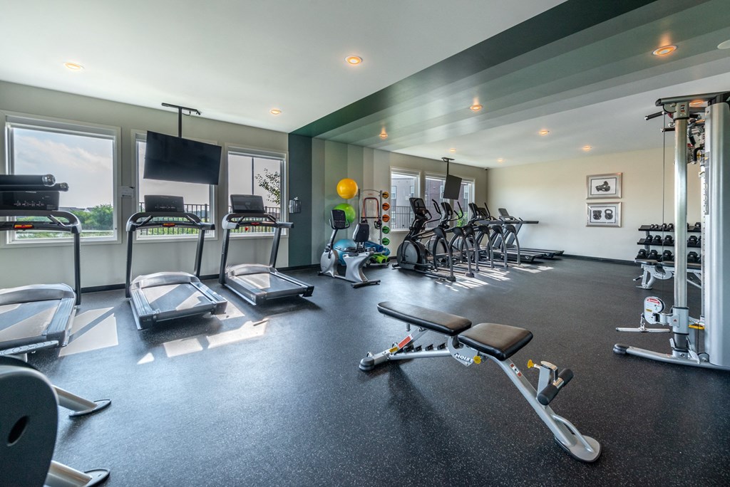 a gym with treadmills and other exercise equipment and windows