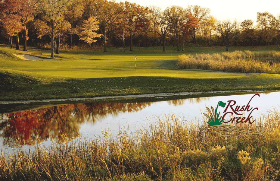 a golf course with a pond and trees in the background
