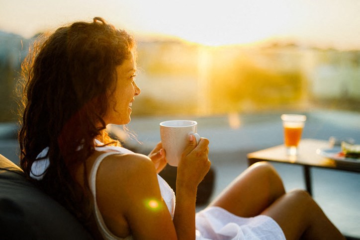 a woman sitting on a couch holding a cup of coffee
