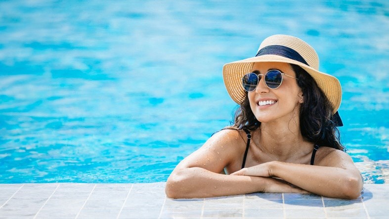 a woman in a hat and sunglasses in a swimming pool