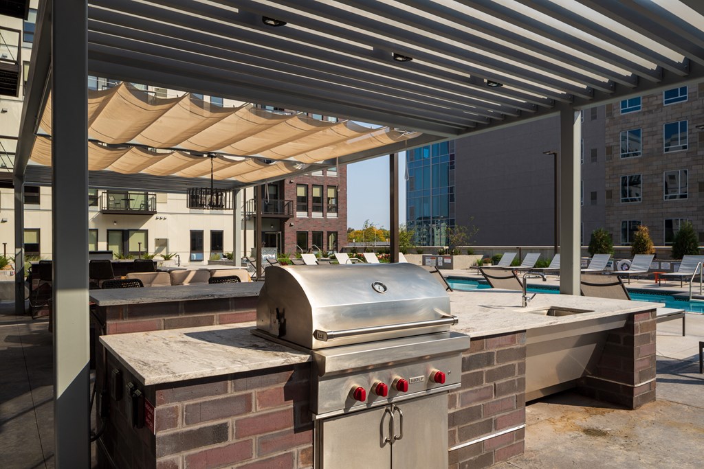 a barbecue grill on a patio next to a swimming pool
