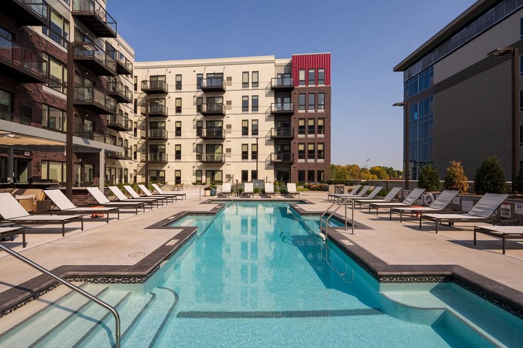 a swimming pool with lounge chairs next to an apartment building