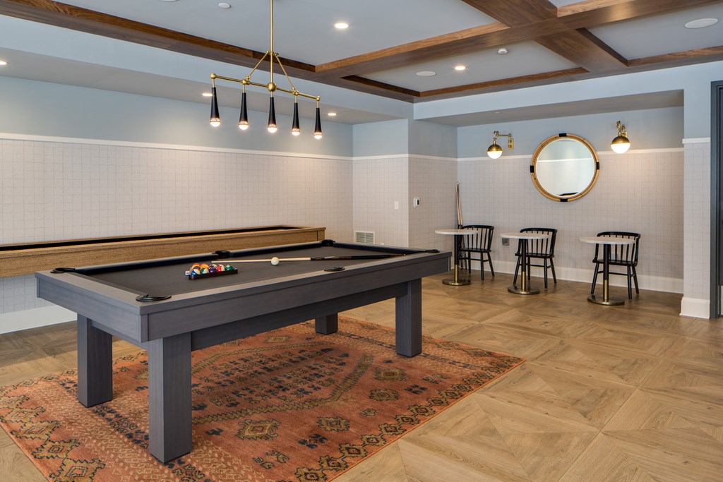 a billiards table in a game room with chairs and a mirror