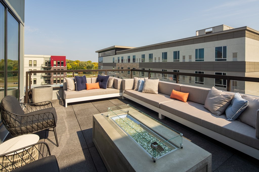 a rooftop patio with couches and a glass table