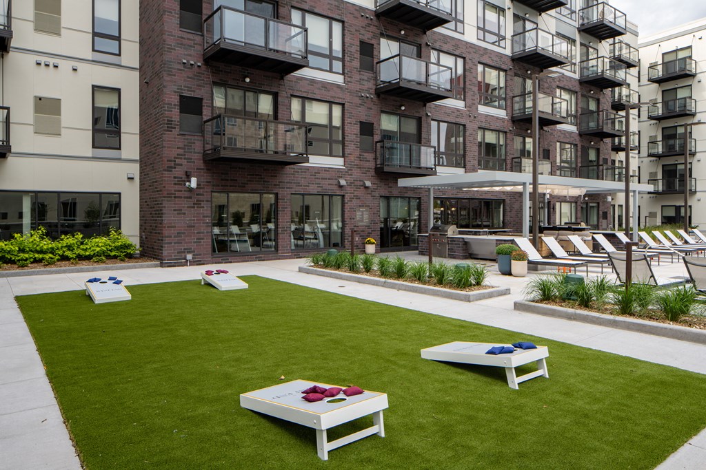 an outdoor living area with grass and benches in front of an apartment building