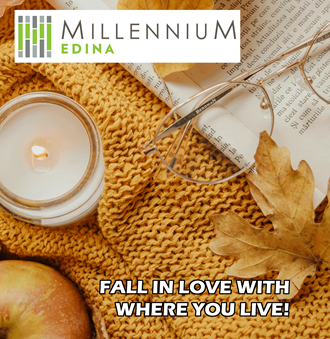 a candle in a jar on a sweater with autumn leaves and an apple