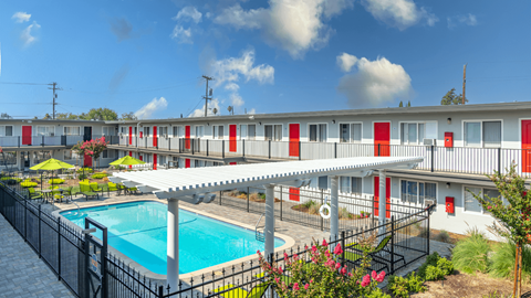 A pool area with a red and white building in the background.