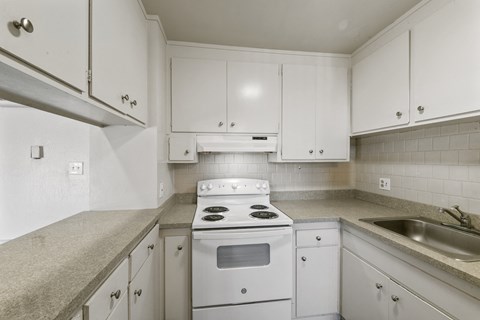 A kitchen with white cabinets and a stove top oven.