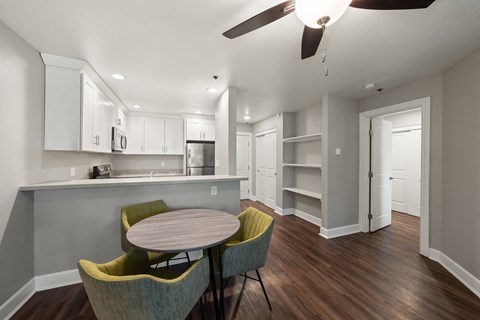 a dining area with a table and chairs and a kitchen in the background
