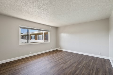 A room with wooden floors and a window showing a view of a building outside.
