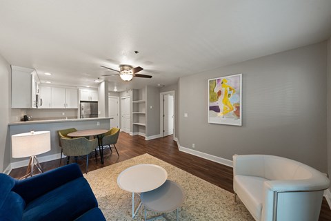 A living room with a blue chair and a painting on the wall.