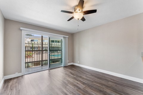 A room with a ceiling fan and sliding glass doors.
