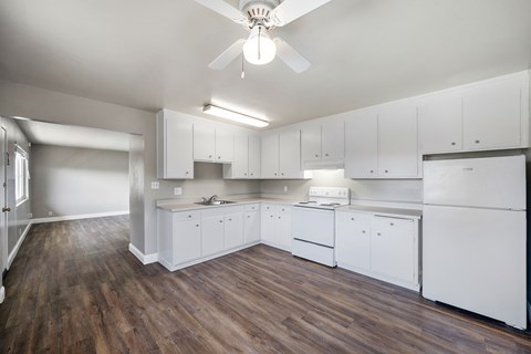 A kitchen with white cabinets and a wooden floor.