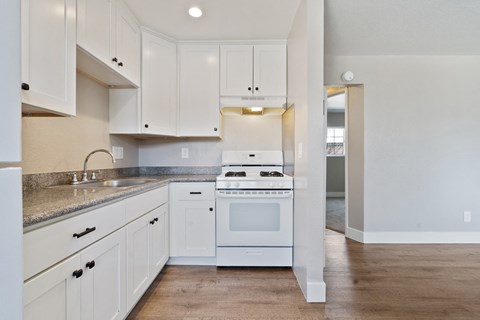 A white kitchen with a stove top oven and sink.