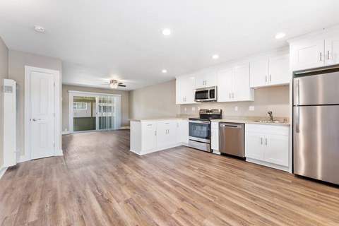 A kitchen with white cabinets and a wooden floor.