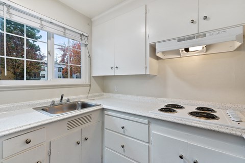 A kitchen with white cabinets and a stove top oven.