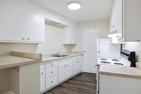 A kitchen with white cabinets and a stove top oven.